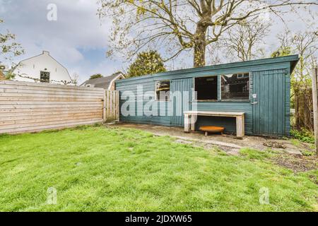 Grange bleue en bois avec banc près d'une clôture en bois dans la cour d'une maison moderne Banque D'Images