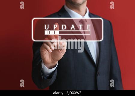 Homme d'affaires touchant l'écran virtuel avec MISE À JOUR de mot et barre d'état sur fond rouge Banque D'Images