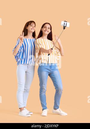 Les sœurs jumelles adolescentes prennent le selfie sur fond beige Banque D'Images