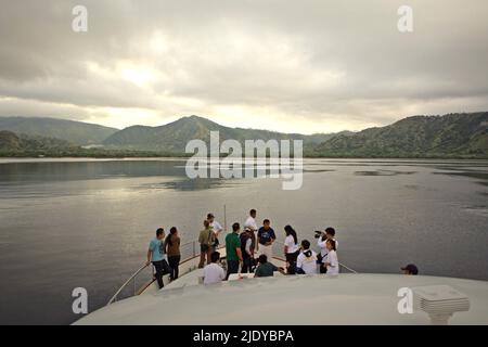 Passagers debout sur l'arc d'un bateau qui se dirige vers l'île Komodo dans la zone du parc national de Komodo à Komodo, à l'ouest de Manggarai, à l'est de Nusa Tenggara, en Indonésie. Banque D'Images