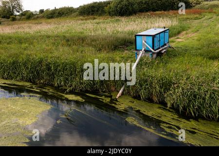 Un grand générateur industriel pompant de l'eau d'une rivière pour la transférer aux terres agricoles à des fins d'irrigation Banque D'Images