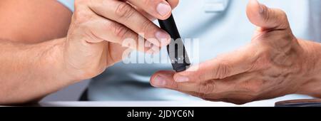 Close-up de la main d'un homme à l'essai le haut sucre de sang avec diabete Banque D'Images