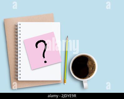 Point d'interrogation sur le pense-bête rose avec crayon et café sur fond de table bleu. Conception de concept d'entreprise et d'éducation. Banque D'Images