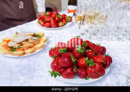 Une table de banquet avec des verres à vin et des assiettes avec des en-cas. Le garçon remplit les verres de champagne. Concept de fête. Mise au point sélective. Banque D'Images