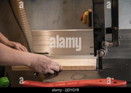 Menuisier non reconnaissable, homme professionnel mains utilisant la scie de taille de panneau machine à bois pour couper le bois dans l'atelier Banque D'Images