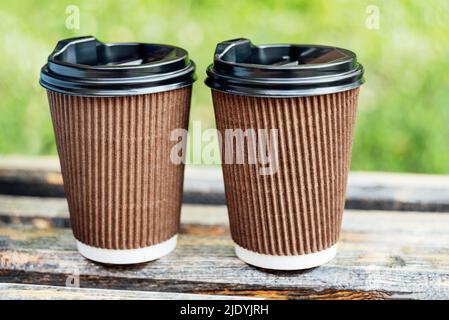 Deux tasses avec boisson chaude à emporter dans le parc sur un banc en bois. Vue rapprochée de deux tasses à café jetables. Romantique date avec café. Réunion d'affaires à emporter. Bonne conversation sur une tasse de thé Banque D'Images