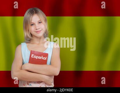 Jeune fille tenant un manuel avec inscription espagnol en langue espagnole sur fond de drapeau de l'Espagne. Apprendre le concept de langue espagnole. Banque D'Images