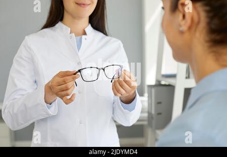 Femme oculiste ou médecin ophtalmologiste au pelage blanc tient des lunettes à la vue du patient Banque D'Images