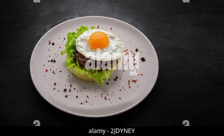 Beefsteak avec œuf, laitue, épices et purée de pommes de terre sur fond sombre Banque D'Images