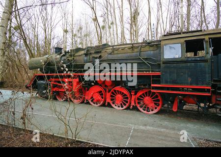 Locomotive à vapeur garée à un terminal. Chemin de fer historique de 1940 en rouge noir. Photo de nostalgie de la technologie passée Banque D'Images