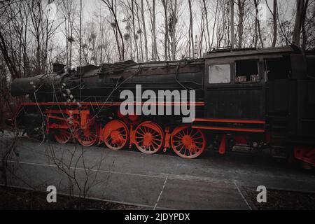 Locomotive à vapeur garée à un terminal. Chemin de fer historique de 1940 en rouge noir. Photo de nostalgie de la technologie passée Banque D'Images