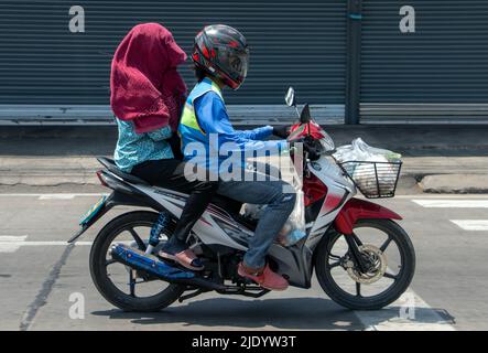 SAMUT PRAKAN, THAÏLANDE, APR 16 2022, Un taxi moto se déplace dans la rue avec une femme cachée sous une serviette Banque D'Images