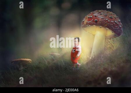 Image composite d'un garçon marchant sous des champignons lumineux dans la forêt. Une image de conte de fées fantasy. Banque D'Images