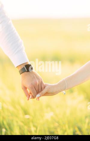 Couple amoureux tient les mains les unes les autres pendant la marche dans la prairie. Gros plan. Banque D'Images