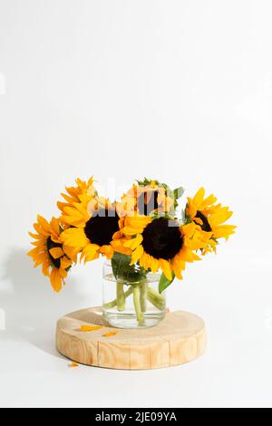 Tournesols lumineux dans un vase en verre sur fond blanc Banque D'Images