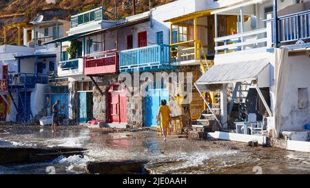 Serres colorées, jet de mer, touriste en robe jaune, balcons, maisons en bois, climat, Golfe de Milos, Île de Milos, Cyclades, Grèce Banque D'Images