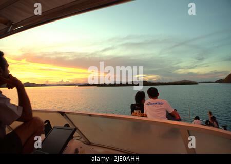 Visiteurs et équipage de bateau appréciant le panorama du bateau autour de l'heure du coucher du soleil près de Pulau Kalong (île de Bat) dans la zone du parc national de Komodo à Komodo, West Manggarai, East Nusa Tenggara, Indonésie. Banque D'Images