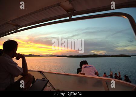 Visiteurs et équipage de bateau appréciant le panorama du bateau autour de l'heure du coucher du soleil près de Pulau Kalong (île de Bat) dans la zone du parc national de Komodo à Komodo, West Manggarai, East Nusa Tenggara, Indonésie. Banque D'Images