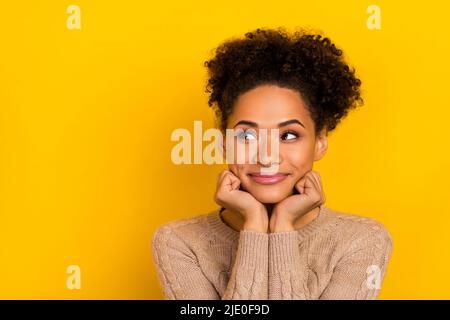 Photo de drôle douce dame habillé beige Pullover bras joues regardant l'espace vide isolé couleur jaune fond Banque D'Images