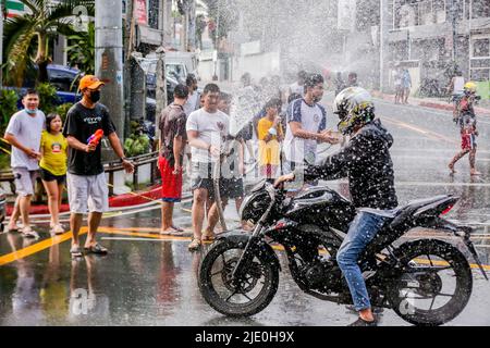 San Juan City, Philippines. 24th juin 2022. Un homme qui fait de la moto est éclaboussé d'eau lors du festival annuel du Wattah-Wattah à San Juan, aux Philippines, au 24 juin 2022. Le festival de Wattah-Wattah est célébré avec une danse de rue vigoureuse et boistereuse, basaan (soulage de l'eau), des défilés et des concerts exécutés par des artistes locaux. Crédit: Rouelle Umali/Xinhua/Alamy Live News Banque D'Images