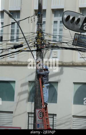 salvador, bahia, brésil - 20 juin 2022 : un homme sur une échelle met le câblage de teva sur un poteau électrique de réseau dans la ville de Salvador. Banque D'Images