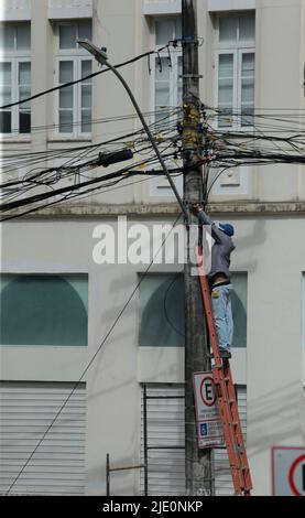 salvador, bahia, brésil - 20 juin 2022 : un homme sur une échelle met le câblage de teva sur un poteau électrique de réseau dans la ville de Salvador. Banque D'Images