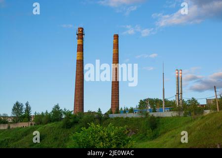 tuyaux d'usine sur le fond de l'herbe verte et du ciel bleu avec des nuages Banque D'Images