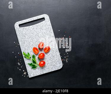 Tableau blanc en marbre épices mûres tomates cerises fond noir. Ingrédients légumes frais Banque D'Images