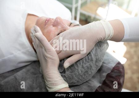 Gros plan de la main d'un médecin d'esthéticienne faisant une procédure médicale de rajeunissement de la peau du visage à une femme. Banque D'Images