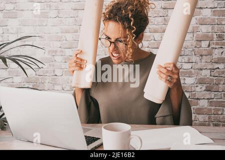 Une femme en colère devant un ordinateur à l'expression mauvaise et stressée. Femme fatiguée travaillant sur un ordinateur portable dans un lieu de travail à domicile. Concept de problèmes avec j Banque D'Images