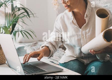Concepteur au bureau à domicile utilisant un ordinateur portable. Femme utilisant un ordinateur portable et la technologie sans fil. Des gens modernes avec l'ordinateur et le papier travaillant en ligne. Intérieur Banque D'Images
