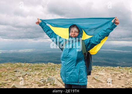 La vue panoramique sur les montagnes de Babia Gora avec une femme drapeau ukrainien célèbre la victoire au sommet d'une montagne. Banque D'Images