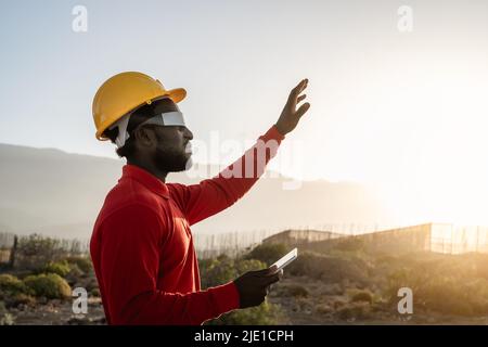 Ingénieur africain travaillant avec des lunettes futuristes sur le chantier de construction - technologie et futur concept d'industrie Banque D'Images