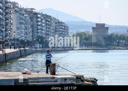 Un pêcheur sur le front de mer de Thessalonique avec l'avenue Nikis et la tour blanche en arrière-plan, Macédoine, Grèce du Nord Banque D'Images