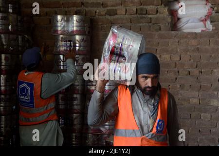 23 juin 2022, Peshawar, khyber pakhtunkhwa, Pakistan: Les travailleurs de la Fondation Alkhidmat chargent des secours dans des camions de livraison pour les victimes afghanes du tremblement de terre à Chamkani. Plus de 1 000 personnes ont été tuées et plus de 1 500 autres blessées après un séisme de magnitude 5,9 qui a frappé l'est de l'Afghanistan avant l'aube le 22 juin, a rapporté l'agence de presse nationale de Bakhtar. Selon les autorités, le nombre de morts devrait augmenter. (Image de crédit : © Hussain Ali/Pacific Press via ZUMA Press Wire) Banque D'Images