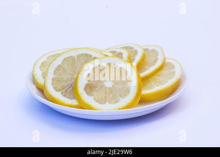 Tranches de citrons sur une plaque blanche isolée sur fond blanc Banque D'Images