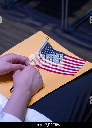 Austin, Texas, États-Unis. 24th juin 2022. Une femme porte un drapeau américain alors que 95 nouveaux citoyens américains de 40 pays étrangers prêtent le serment d'allégeance dirigé par un juge fédéral à la bibliothèque centrale d'Austin. La cérémonie est l'une des nombreuses manifestations de citoyenneté prévues cet été dans le centre du Texas. (Image de crédit : © Bob Daemmrich/ZUMA Press Wire) Banque D'Images