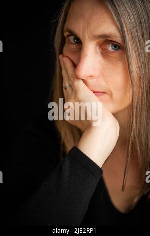 Calme. Un portrait d'une femme mûre regardant candidement et avec suspicion à l'égard de l'appareil photo. Banque D'Images