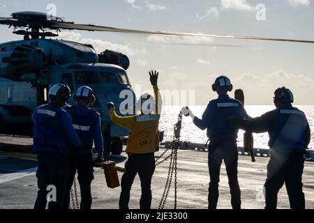 AVIATION DE L'OCÉAN PACIFIQUE (22 juin 2022) compagnon de bateau (manutention) Airman Garrett Solomon, de Ewa Beach, Hawaii, au centre, affecté au navire d'assaut amphibie USS Essex (LHD 2), signale à un super étalon CH-53E, attaché au Squadron d'hélicoptères lourds marins (HMH) 462, pendant les opérations de vol à bord d'Essex, 22 juin 2022. Essex mène actuellement des opérations de routine dans la flotte américaine 3rd. (É.-U. Navy photo par Mass communication Specialist 3rd Class Isaak Martinez) Banque D'Images