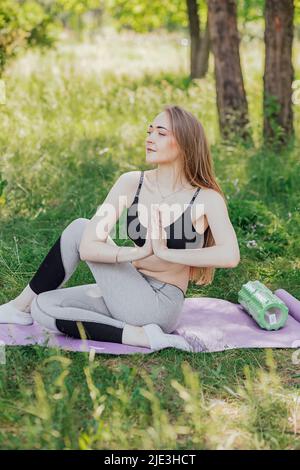 Femme de yoga sur l'herbe verte fille se détend dans le champ. Femme de yoga dans le parc vert fille faisant de la gymnastique à l'extérieur. Méditer la femme dans la méditation dans le yoga p Banque D'Images
