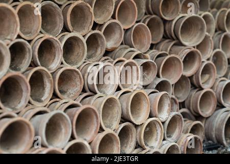 Gros plan des piles de pots de fleurs de terre cuite anciens et altérés dans le hangar de jardinage Banque D'Images