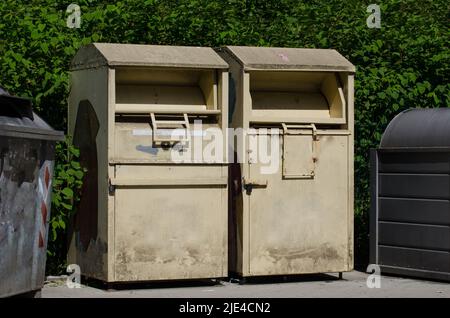 deux poubelles de collecte de charité sales / banques de vêtements pour la collecte de vêtements et de chaussures anciens et usagés se tenant à un point de recyclage Banque D'Images