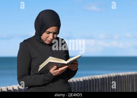 Femme musulmane ciblée lisant un livre à l'extérieur Banque D'Images