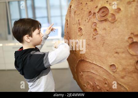 L'enfant tourne le modèle de la lune dans le musée Banque D'Images