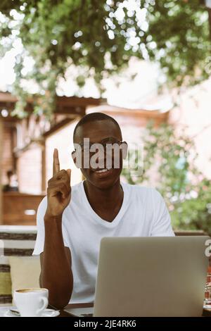 Vertical multiculturel, mélange homme couru dans des lunettes avec ordinateur portable, indexation, pointant vers le haut, de nouvelles idées. Travailler, étudier en ligne Banque D'Images