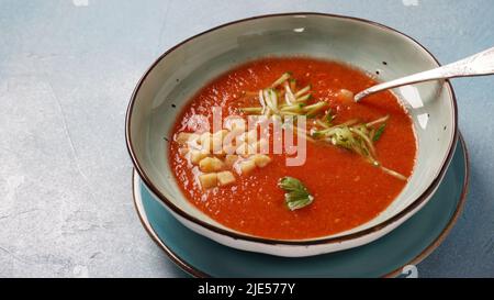 Bol avec soupe de tomates Gazpacho maison, avec croûtons et tranches de concombre. Soupe espagnole froide à base de tomates Banque D'Images