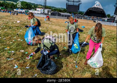 Pilton, Royaume-Uni. 25th juin 2022. Des milliers de bénévoles (beaucoup de collecte d'argent pour les organismes de bienfaisance) nettoient les déchets laissés par les festivaliers la nuit précédente (dans ce cas à l'étape Pyramid). Le travail est nécessaire en dépit de la devise du festival pour «ne laisser aucune trace» - le Glastonbury Festival 50th 2022, digne ferme. Glastonbury, Credit: Guy Bell/Alamy Live News Banque D'Images