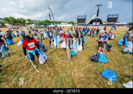 Pilton, Royaume-Uni. 25th juin 2022. Des milliers de bénévoles (beaucoup de collecte d'argent pour les organismes de bienfaisance) nettoient les déchets laissés par les festivaliers la nuit précédente (dans ce cas à l'étape Pyramid). Le travail est nécessaire en dépit de la devise du festival pour «ne laisser aucune trace» - le Glastonbury Festival 50th 2022, digne ferme. Glastonbury, Credit: Guy Bell/Alamy Live News Banque D'Images