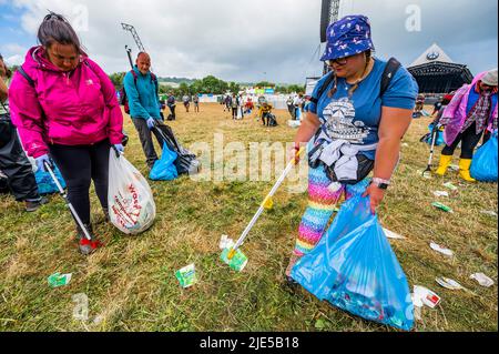 Pilton, Royaume-Uni. 25th juin 2022. Des milliers de bénévoles (beaucoup de collecte d'argent pour les organismes de bienfaisance) nettoient les déchets laissés par les festivaliers la nuit précédente (dans ce cas à l'étape Pyramid). Le travail est nécessaire en dépit de la devise du festival pour «ne laisser aucune trace» - le Glastonbury Festival 50th 2022, digne ferme. Glastonbury, Credit: Guy Bell/Alamy Live News Banque D'Images