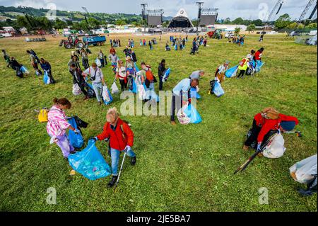 Pilton, Royaume-Uni. 25th juin 2022. Des milliers de bénévoles (beaucoup de collecte d'argent pour les organismes de bienfaisance) nettoient les déchets laissés par les festivaliers la nuit précédente (dans ce cas à l'étape Pyramid). Le travail est nécessaire en dépit de la devise du festival pour «ne laisser aucune trace» - le Glastonbury Festival 50th 2022, digne ferme. Glastonbury, Credit: Guy Bell/Alamy Live News Banque D'Images